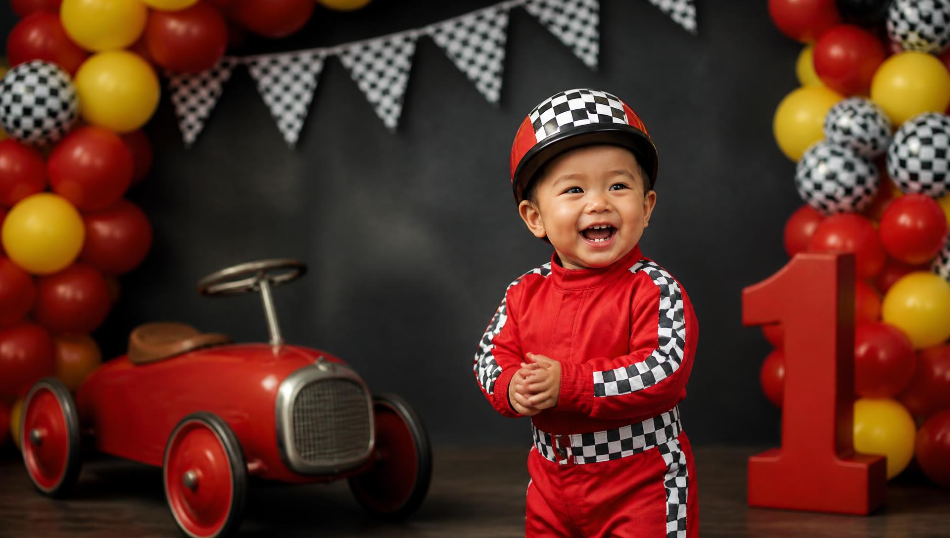 Filipino toddler in a red racing suit at a checkered-flag first birthday setup